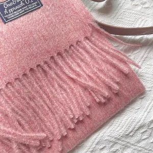 Close-up of pink wool scarf with fringe and dark blue woven label detail