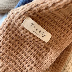 Detail of waffle knit texture and trendy accessories tag on brown shawl wrap