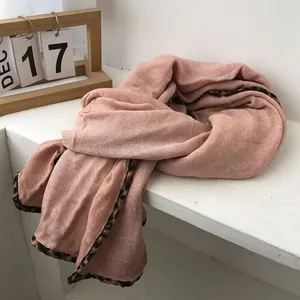 Detail showing the soft fabric texture and leopard print edge of the pink scarf