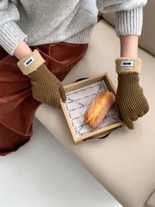 Detail von Strickhandschuhen mit beigen Lammfell-Bündchen und ERET-Stoffetikett