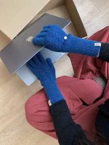 Detailed cable knit pattern on royal blue wool gloves while using a laptop