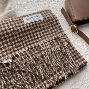 Detail shot of brown houndstooth wool scarf with long fringe and brand logo label