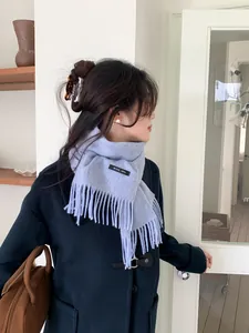 Detail of 100% wool scarf with tassel fringe on a model wearing a navy duffle coat