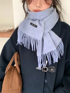 Close-up of 100% wool light blue scarf with tassel detail and material label