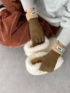 Detail von Strickhandschuhen mit beigem Kunstlammfell-Bund und blauem ERET-Stoffetikett