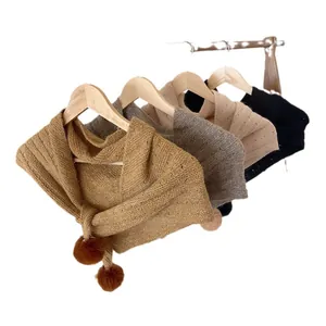 Winter knitted triangle shawl with pom-pom ties in brown, beige, and black colors