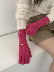 Detail of cable knit wool blend gloves in vibrant rose red with elegant charm decoration