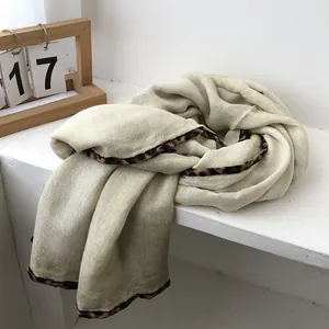 Detail of cream cotton-linen scarf featuring a stylish leopard print border and fine texture