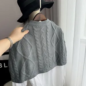 Detail of grey cable knit shawl with thick twist patterns on white shirt