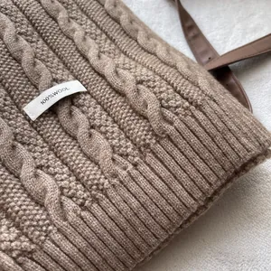 Detail of cable knit wool scarf with 100% wool label and soft texture