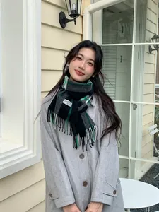 Detailed view of British style green plaid cashmere scarf paired with a grey wool coat