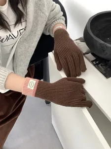 Close-up of brown knit gloves with ribbed texture and pink contrast wrist cuffs