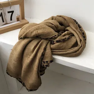 Detail of dark camel cotton scarf featuring stylish leopard print edges and soft texture