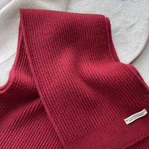 Nahaufnahme der dunkelroten Rippstrick-Wollschal-Textur mit elegantem Stoffetikett