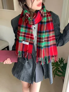 Detail of red plaid wool scarf with soft tassels and brand tag for winter