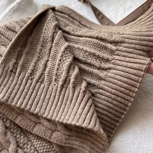 Detailed close-up of brown cable knit pattern and ribbed cuff on wool blend scarf