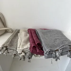 Dettaglio di sciarpe in cotone lino a nido d'ape con nappe e perle di legno decorative