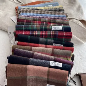 Multiple 100% wool scarves in various plaid patterns and solid colors for winter warmth