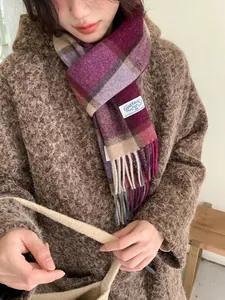 Detailaufnahme des dicken Wollschals mit Karomuster, Fransen und Markenlabel in Violett