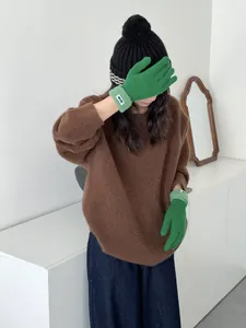 Detailansicht der grünen Grobstrickhandschuhe mit Kontrastrand zu einem braunen Pullover