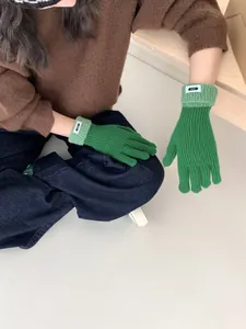 Detail von grünen Strickhandschuhen mit ERET-Logo und Kontrastbündchen in Lifestyle-Szene
