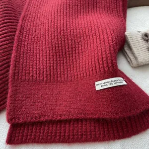 Detailansicht eines dunkelroten Rippstrickschals mit modischem rechteckigem Textiletikett