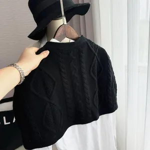 Detail of black cable-knit shawl over a white shirt with textured knit pattern