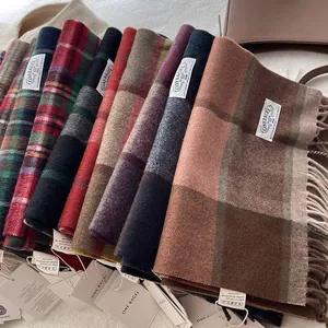 Stack of wool plaid scarves with fringes and brand tags in various classic patterns