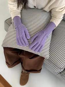 Detailed view of purple cable knit gloves with cozy ribbed cuffs and a small brand label