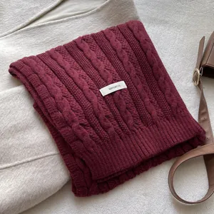Close-up of burgundy cable knit wool scarf showing thick texture and wool label