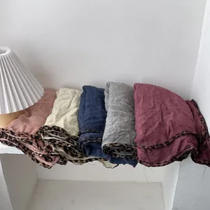 Chic leopard trim cotton linen scarves in five colors displayed with a desk lamp