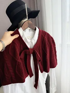 Detail of burgundy cable knit shawl with bow tie and textured weave pattern