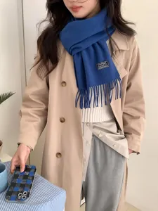 Detail of the royal blue wool scarf with fringe and a chic minimalist woven brand label