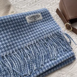 Detail of blue and white houndstooth wool scarf with long tassels and woven brand label