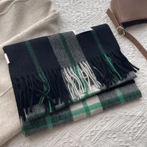 Close-up of matcha hazelnut plaid cashmere scarf with fringes and branded woven label