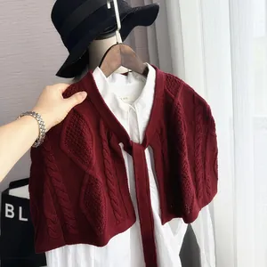 Close-up of wine red cable knit shawl featuring self-tie straps over a white shirt