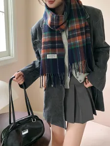 Detail of soft wool blend plaid scarf with tassels and ONEBAGEL brand tag on dark coat