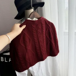 Close-up of burgundy cable-knit sweater vest with intricate diamond pattern detail