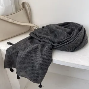 Dettaglio di sciarpa grigio scuro in cotone e lino con motivo a quadretti e nappe