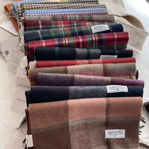 Macro detail of various plaid 100% wool scarves with soft twill texture and brand tags