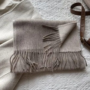 Close-up of taupe 100% wool scarf featuring soft fringe details and premium woven texture