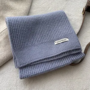 Nahaufnahme der hellvioletten Strickschal-Textur mit weißem rechteckigem Design-Label