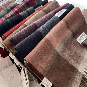 Detailed pile of wool blend scarves with classic check patterns and tassel edges