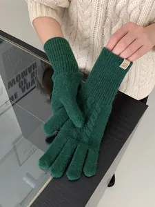Macro detail of forest green wool blend knit glove with classic cable pattern and rib cuff