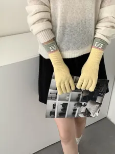 Detail of long knitted touchscreen gloves featuring yellow, pink, and green patchwork colors