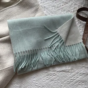 Detailed macro view of two-tone light mint and beige wool scarf with fringe edges