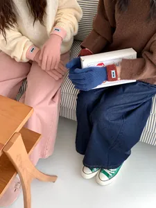 Detail der Strickbündchen und minimalistischen Etiketten an rosa und blauen Handschuhen