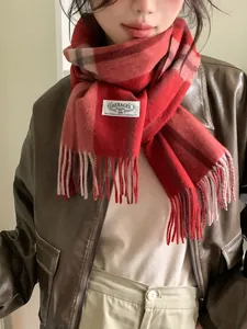 Close-up of red plaid cashmere scarf with soft fringes and authentic woven brand label