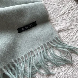 Detail shot of mint green 100% wool scarf showing soft texture and fringe edges