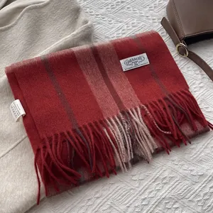 Close-up of the brand label and soft fringe details on a striped cashmere wool scarf